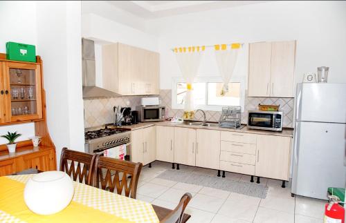 罗安达CASA NATALIA - Guesthouse的厨房配有白色橱柜、桌子和冰箱。