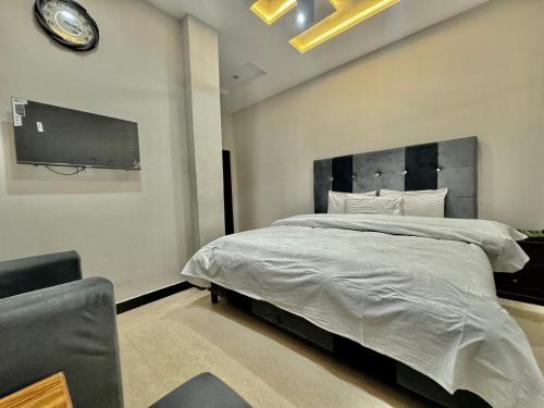 伊斯兰堡Al Atif Hotel的卧室配有一张大床,墙上挂着时钟