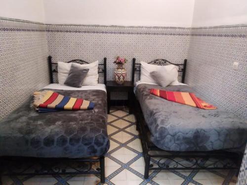 马拉喀什HOTEL EL AMAL的两张睡床彼此相邻,位于一个房间里