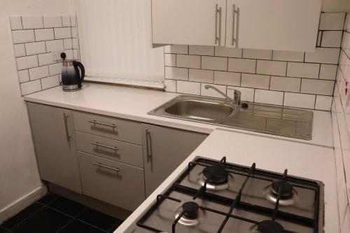 利物浦Goodison Accommodation的一间带炉灶的厨房 水槽旁的顶部烤箱