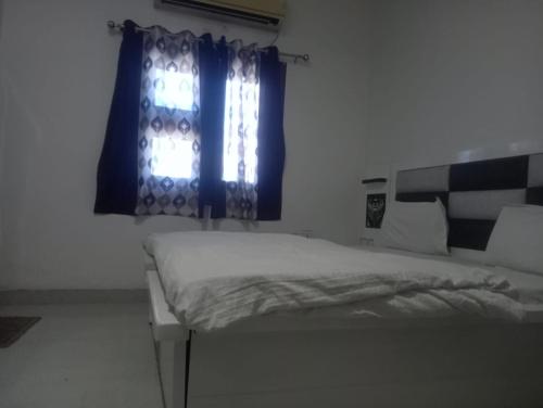 阿姆利则Gurjeet Hotel by Naavagat的一间卧室配有床和蓝色窗帘的窗户