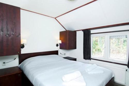 奥特罗Korhoen - 6p HeideBungalow met bedstee的一间卧室设有两张床和窗户。
