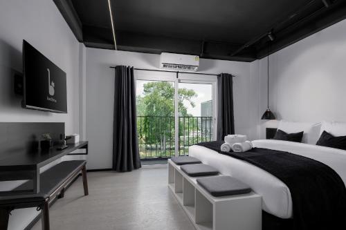 查汶BedTime Hotel Samui的一间卧室配有一张带书桌的床和窗户。