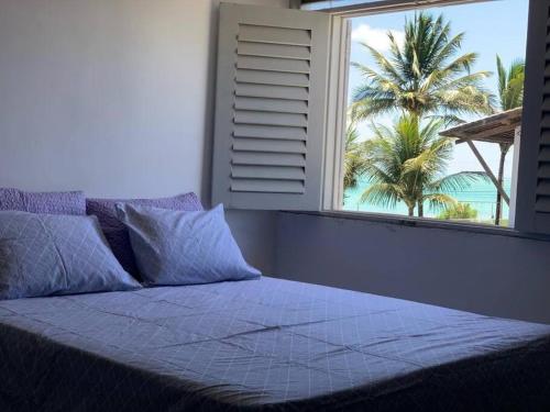 卡贝德卢Casa de frente para o mar (Front beach house)的一间卧室设有一扇带棕榈树的大窗户