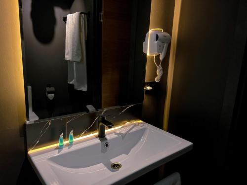 阿拉木图Atlas Hotel的一间带镜子和摄像头的盥洗盆的浴室