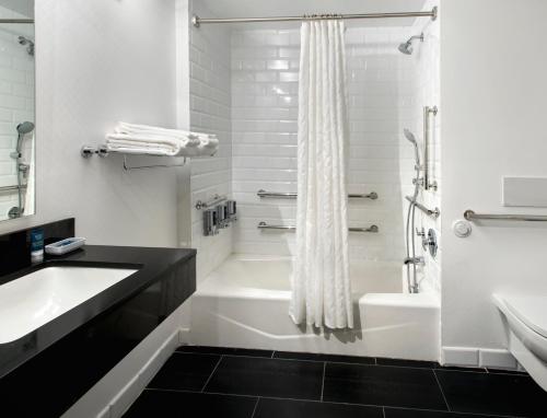 纽约曼哈顿苏豪村福朋喜来登酒店的白色的浴室设有浴缸、水槽和淋浴。