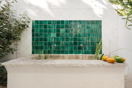 塔维拉Altanure - Almatere Food Forest Boutique Hotel的浴室设有绿色的瓷砖墙,并提供一些水果