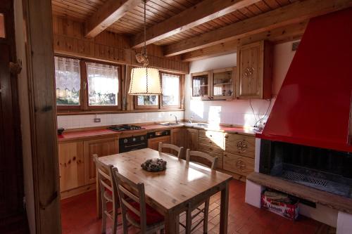 克雷亚佐App Carolina的厨房配有带椅子的木桌和红色用具
