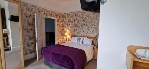阿博伦Hazeldene的一间卧室配有一张带紫色毯子的床