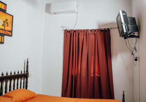 圣达菲InstaLate Hostel的一间卧室配有红色窗帘和电视
