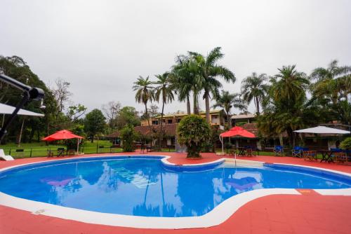 伊瓜苏港HOTEL TROPICAL IGUAZU的度假村内的大型游泳池,配有桌子和遮阳伞