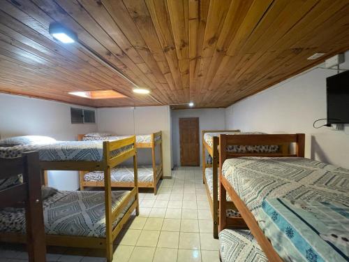 塔尔卡Residencial Don Santiago的客房设有三张双层床和木制天花板。
