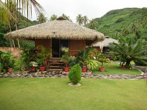PareaRops Location Huahine bungalow premium的草屋顶和草地庭院的小屋