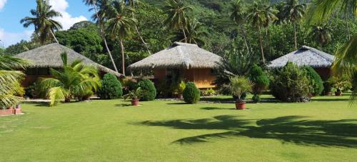 PareaRops Location Huahine bungalow premium的草场上有两个小屋的度假胜地