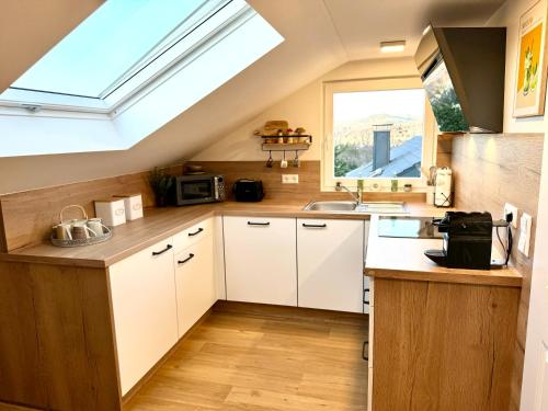加格瑙Schwarzwaldliebe Ferienwohnung mit eigenem Garten的厨房配有白色橱柜和天窗。