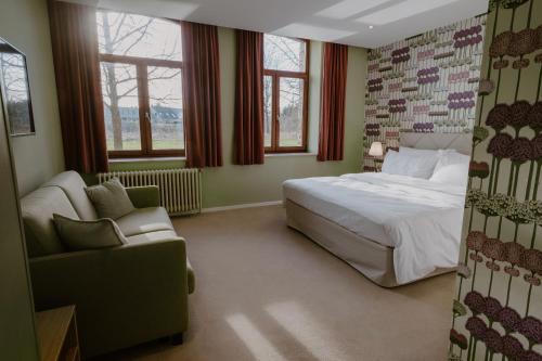博尔赫隆Château de Looz的一间卧室配有一张床、一张沙发和一把椅子