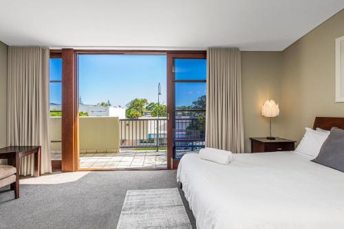 拜伦湾Byron Bay Accom Unit 6 21-25 Fletcher Street - A Seventh Heaven的酒店客房设有一张床和一个阳台。