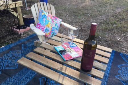 马莱尼White Jacaranda Tiny House的一瓶葡萄酒和一张坐在长凳上的袋子