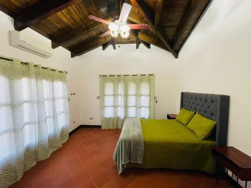 科潘玛雅遗址Las guacamayas House的一间卧室配有绿色的床和吊扇