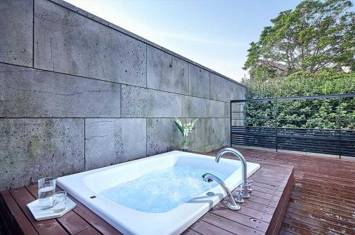 西归浦市Lotte Resort Jeju Artvillas的木制甲板上的一个浴缸