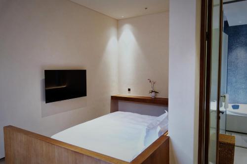 扬州重构·冰瓯馆人文度假民宿(扬州东关街店)的卧室配有一张床,墙上配有电视。