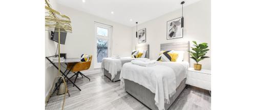 特威克纳姆City Elegance: Spacious 2BR for Urban Comfort的一间卧室配有两张床和一张书桌