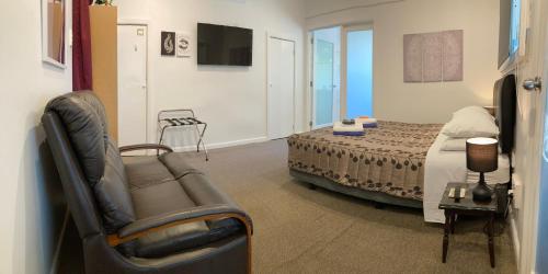 吉斯伯恩Gisborne Dream Suite的一间卧室配有一张床、一张沙发和一把椅子