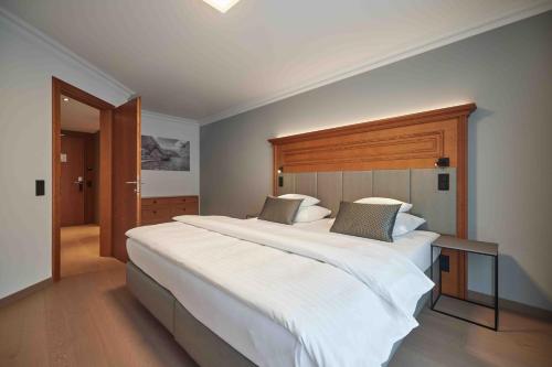 贝希特斯加登Hotel EDELWEISS Berchtesgaden Superior的卧室配有一张白色大床和木制床头板