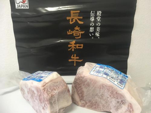 长崎Wagyu hostel nedoko的黑牌前的两块肉