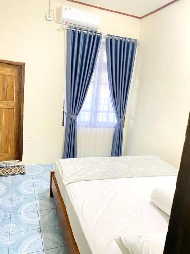 纳闽巴霍Cendana Guesthouse Labuan Bajo2的一间卧室配有蓝色窗帘和一张床