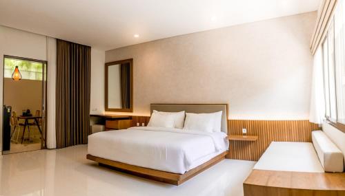 勒吉安D'Green Kuta Managed by ARM Hospitality的卧室配有一张白色大床和一张书桌