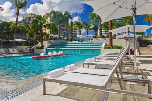 圣胡安圣胡安孔查万丽酒店的毗邻度假酒店的带椅子和遮阳伞的游泳池