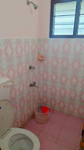 阿勒皮Shakthi Residency的一间带卫生间的浴室和粉红色的瓷砖墙