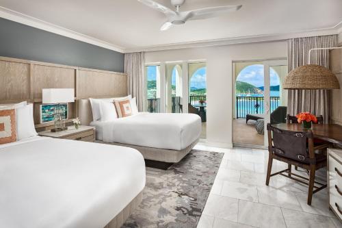 本纳The Ritz-Carlton St. Thomas的酒店客房设有两张床、一张桌子和一台电视。