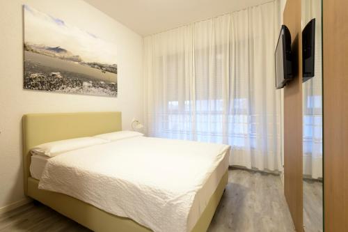 卢加诺切雷西奥酒店的白色的卧室设有床和窗户