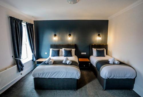卡莱尔坎布里亚公园酒店的配有两张床铺的蓝色墙壁和窗户
