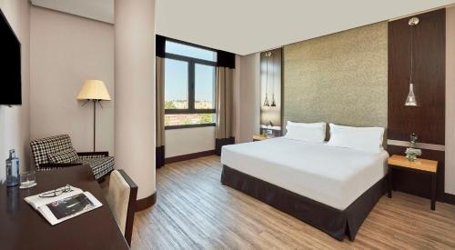 赫雷斯-德拉弗龙特拉NH阿维尼达赫雷斯酒店的酒店客房设有一张大床、一张桌子和一把椅子。