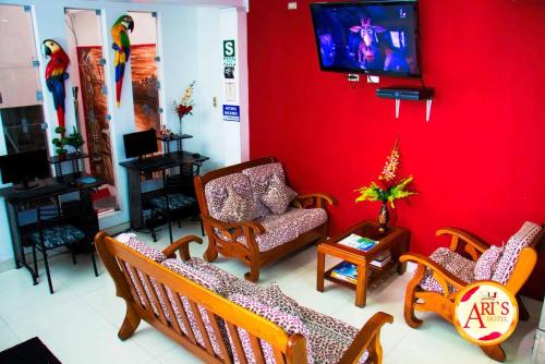 伊基托斯ALLISON HOTEL的客厅配有椅子和红色墙壁上的电视