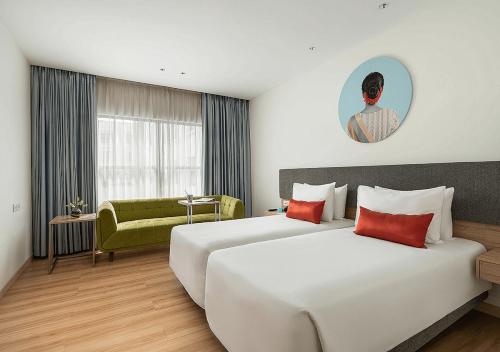海得拉巴Greenpark Hyderabad的酒店客房,设有两张床和一张绿色沙发