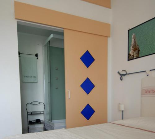 努奥罗Nughe 'e' Oro Guesthouse的卧室配有一张床铺,墙上有蓝色的方形