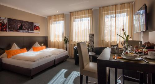 慕尼黑GS酒店的一间卧室配有一张床铺和一张桌子,还有一间用餐室