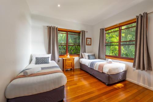拜伦湾拜伦湾腹地塞蒂亚度假屋的一间卧室设有两张床和两个窗户。