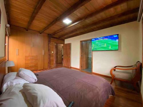 PauteAlegre villa con piscina para uso familiar de 3 dormitorios的卧室配有一张大床,墙上配有电视