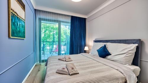 尼彻兹Rezydencja Niechorze 225 - 5D Apartamenty的一间卧室设有一张带蓝色墙壁和窗户的大床