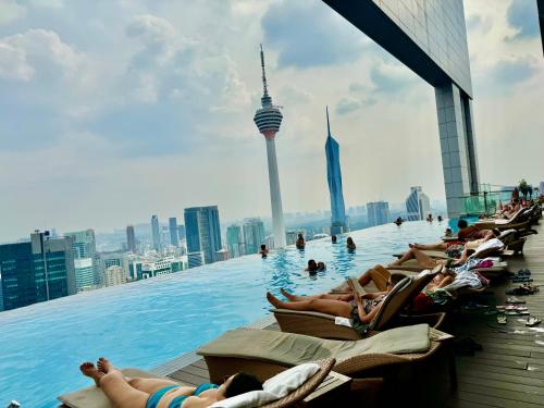 吉隆坡Platinum Suites KLCC by Classy的一群人躺在建筑物屋顶的无边游泳池里