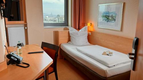 博特罗普博特罗普莱茵鲁尔酒店的酒店客房配有一张床、一张书桌和一部电话