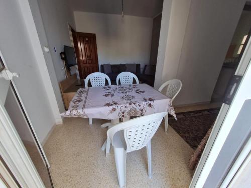 GabèsBienvenue dans votre appartement的一张带四把椅子的白色桌子和一张粉红色的桌布