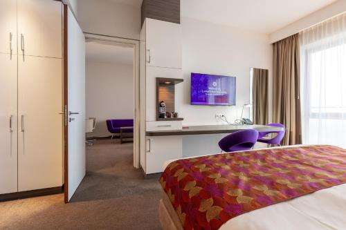 兹沃勒兹沃勒流明酒店的配有一张床和一张书桌的酒店客房