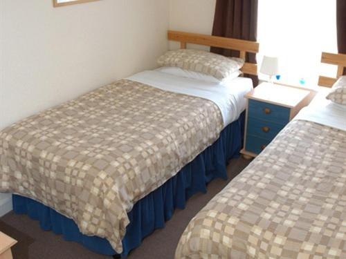 福克斯通肯特米尔旅馆的酒店客房设有两张床和床头柜。