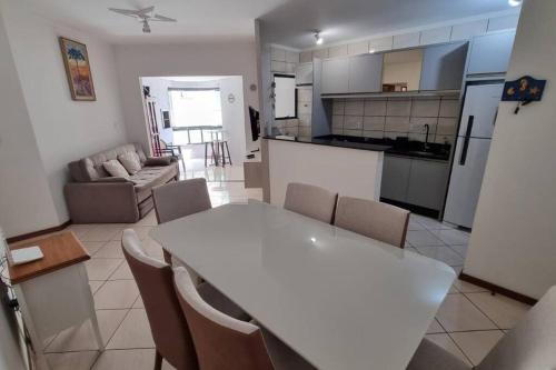 伊塔佩马Apartamento pé na areia em Itapema.的厨房以及带白色桌椅的起居室。